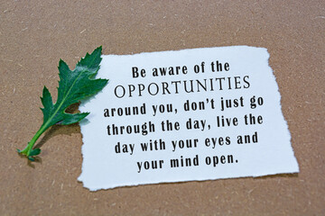 Motivational and inspirational quote on white paper with flowers on wooden desk.