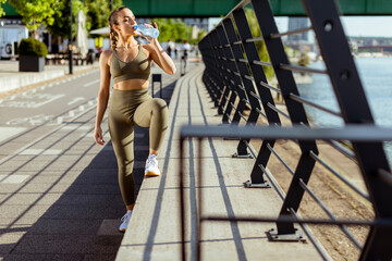 Young woman taking a break during exercise on the river promenade