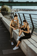 Young women in sportswear exercising on a river promenade