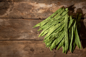 Flat green beans (Phaseolus vulgaris) on an old wooden table. with copy space.