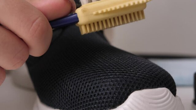 Cleaning a sneaker with a shoe care brush. close-up slow motion