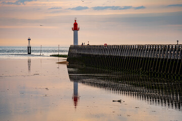 Lighthouse at the entrance to the harbor on the coast of Normandy in France.