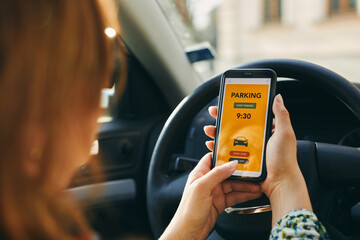 Woman using mobile parking app on smartphone. Driver using smartphone to pay for parking. Car park application on mobile phone. Paying for parking using fast payment online