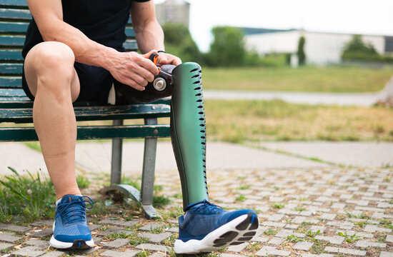 Active man adjusting his prosthetic leg before walking outdoor in the park