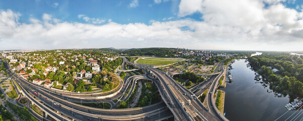 Aerial skyline cityscape view of Belgrade, Serbia, in the morning. Aerial  drone view of   Ada Ciganlija lake, hippodrome and traffic driving over intersection in Belgrade. Urban scene - obrazy, fototapety, plakaty