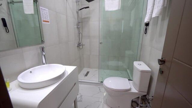 A small modern bathroom with a light white dressing table, mirror frame and accessories. White subway tiles in the bathroom and shower. panorama of the restroom. Realty. interior.