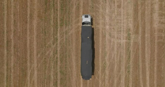 Truck loaded with Hay bales leaving a field, drone footage.