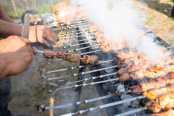 men's hands are cooking a barbecue on the grill in close-up. smoke cooking meat on the street