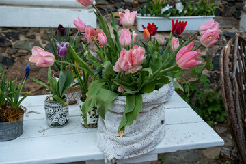 Beautiful bouquet is packaged in kraft paper in flower shop. Flowers in metal and glass container, between wooden boxes, modern ecological design, loft, craft.