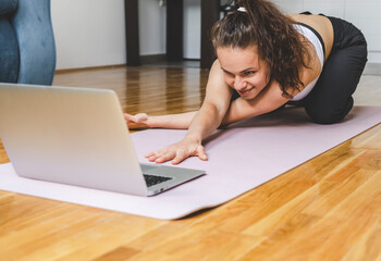 Girl doing yoga at home with her laptop.