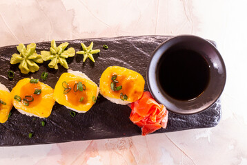 rolls with yellow sauce on a black plate top view