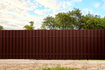 Seamless brown metal profile picket fence. Side wall high and long. Opaque surface vertical lines....