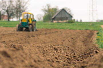 Plowing and sowing the soil with an old farm tractor Belarus in an agricultural field in spring,...