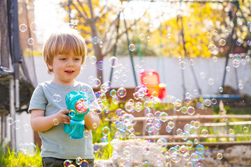 Little boy play with soap bubbles holding bubble gun