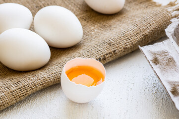 Raw white farm chicken eggs with egg yolk on white rustic table