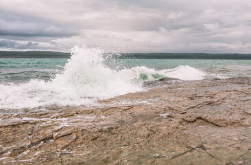 Dramatic scene with Sea waves, rocky seashore and blue clouds
