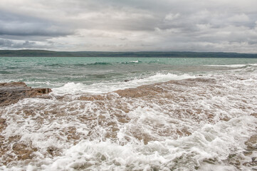 Dramatic scene with Sea waves, rocky seashore and blue clouds