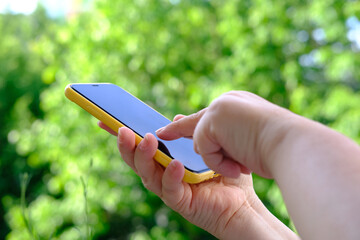close-up of female hand hold smartphone with blank screen mobile in gargen, beautiful blurred...