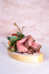 bruschetta with a piece of meat and capers close-up.
