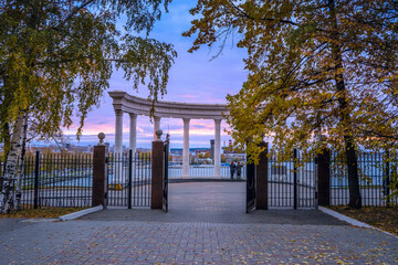 The gate of the autumn park with access to the rotunda and a view of the pond. Izhevsk, Russia