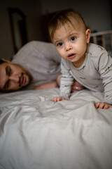 dad is lying on the bed with his little son