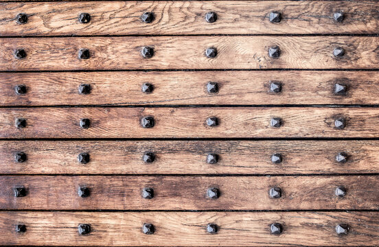 Wooden background of old riveted boards. Vintage front door in the medieval city of Italy. Ancient wooden gate. Old city streets, beautiful doors and unusual door handles.