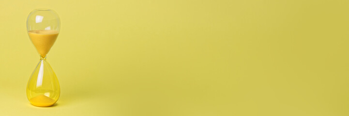 Yellow hourglass on yellow background banner. Passing time or deadline concept.