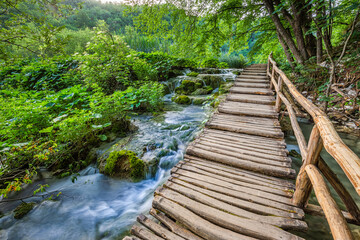 Obraz premium Plitvice, Croatia - Wooden walkway in Plitvice Lakes National Park on a bright summer day with crystal clear turquoise water, small waterfalls and green summer foliage
