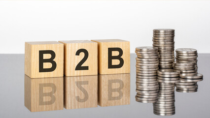 b2b - text on wooden cubes on a cold grey light background with stacks coins