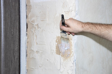 The painter primes the wall with a primer. Repair and priming of the wall before applying the plaster. Painting and construction work and interior decoration.
