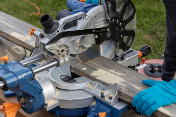 Miter circular saw photographed in the process of work. Tool for carpentry. A man works with a tool. The worker saws the boards. Sawmill. Miter saw for cutting wood at work.