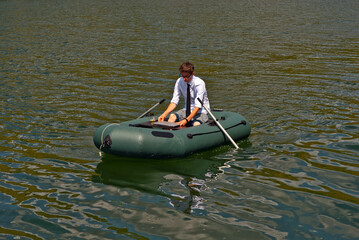 A man in a white shirt on an inflatable boat. Businessman with laptop resting on the lake. The...