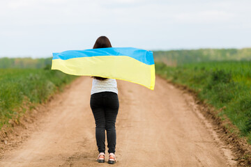 Woman with Ukrainian flag in wheat field.Happy woman celebrating Independence Day.