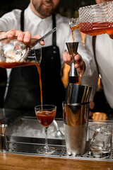 close-up on shaker cups and a wineglass into which the bartender pours a drink