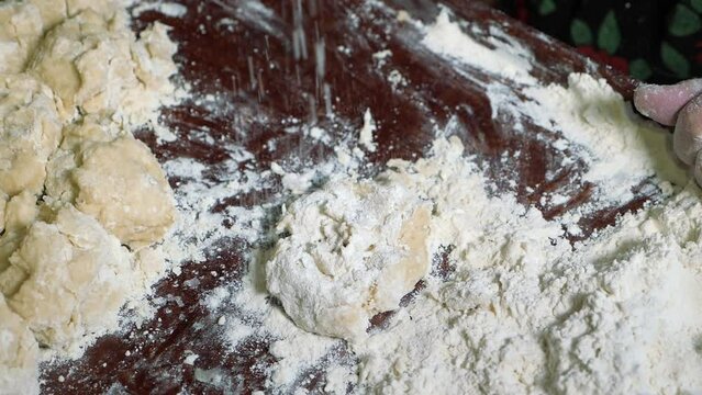 Wrinkled hands of an elderly man knead the dough and make balls of kolobok.
