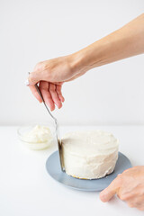 Delicious creamy cake that the girl spreads over the whipped cream with a spatula, the cake is ready for decoration.