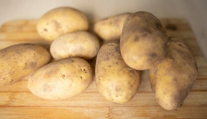 peeled potatoes lie on the surface of a wooden table in the kitchen. Potato supply problems, sales restrictions, global famine, potato shortage