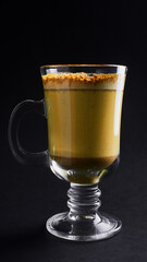 coffee latte with turmeric and milk in a glass cup on a black background