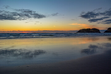 Fototapeta premium Sunset at Canon Beach with Haystack Rock and sun going down, Ecola beach.