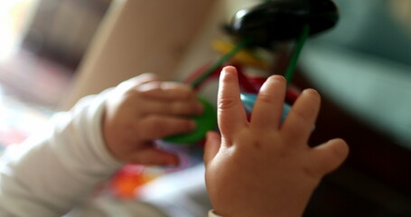 Baby hands holding play toy, close-up infant plays with child development toys