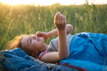 The girl is dissatisfied with scratching mosquito bites, child sleeps in a sleeping bag on the...