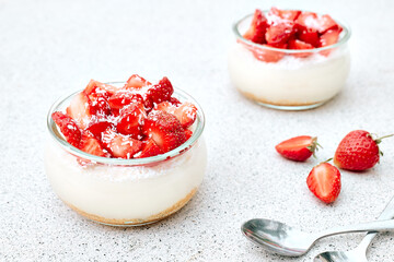 Strawberry desserts with fresh strawberries, cream cheese or natural yoghurt and oat granola in glass jars on light surface. Delicious healthy organic summer snack or breakfast.