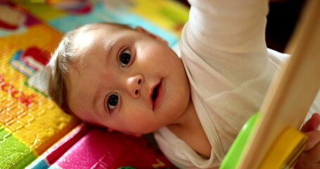 Baby hands holding play toy, close-up infant plays with child development lying on floor