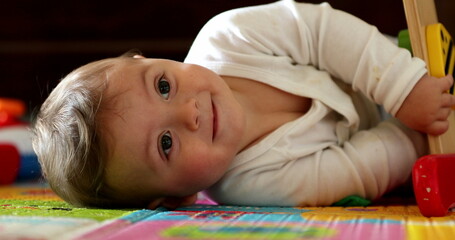 Baby hands holding play toy, close-up infant plays with child development lying on floor