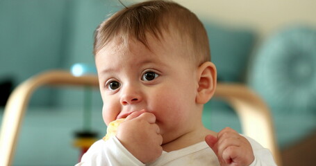 Baby face eating healthy snack fruit, infant child eats piece of apple fruit