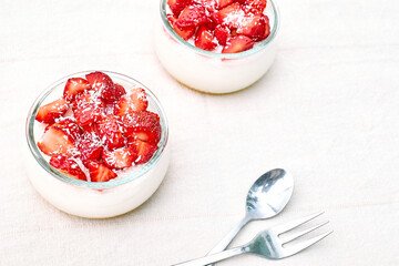 Strawberry desserts with fresh strawberries, cream cheese or natural yoghurt and oat granola in glass jars on linen tablecloth. Delicious healthy organic summer snack or breakfast