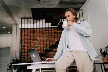 Man drinks coffee at the workplace In a stylish office or coworking space, an employee chills with a cup of tea - Powered by Adobe
