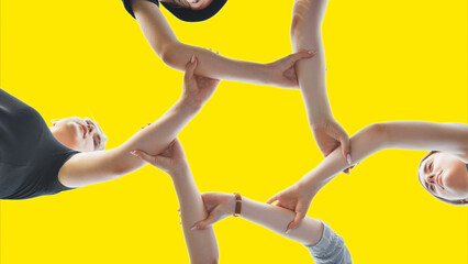 Friends join their wrist and make a circle on a yellow background. Strong friendship concept.