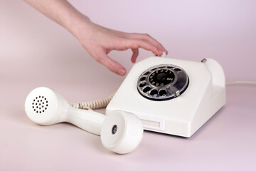 Girl hand holding vintage telephone receiver with phone on light background. Communication 80s. minimal concept.