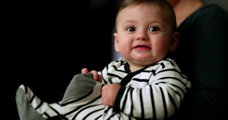 Adorable cute baby infant wearing pijamas at night, toddler putting feet in mouth